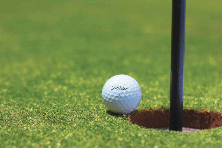 Ein Foto eines grünen Rasens mit einem kleinem Golfball. Er symbolisiert Strategie und Management.