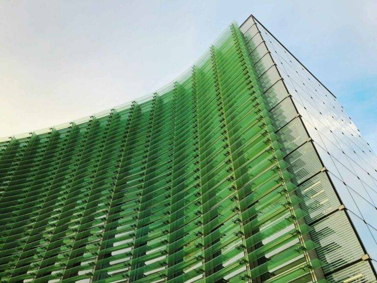 Eine Photographie eines verglasten Hochhauses umhüllt mit grünem Glas.