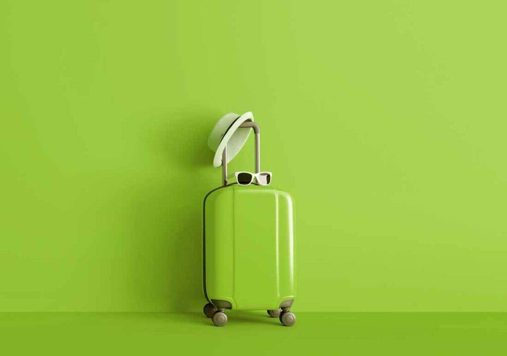 Ein Bild von einem grünen Reisekoffer vor einem grünen Hintergrund. Am Koffergriff hängt ein weißer Hut. Der Koffer steht für Veränderung.