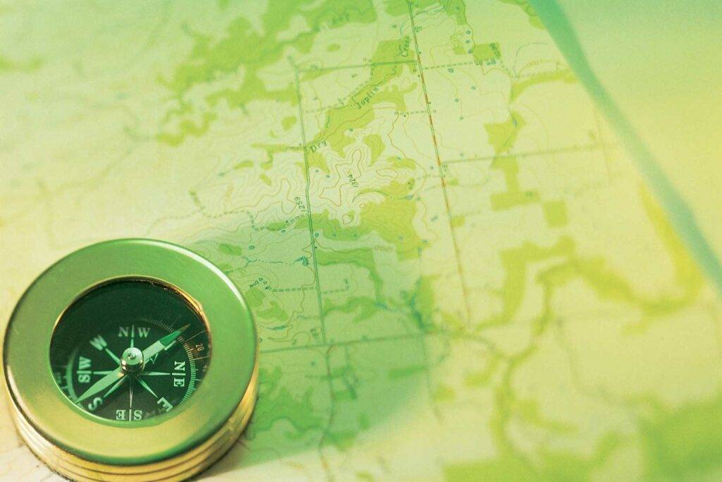 Eine Abbildung einer Karte und eines Kompass in grün, als Symbol von Wandel.