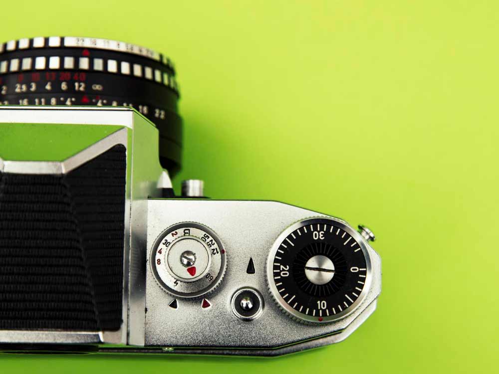 Ein Bild von einer Digitalkamera auf einem grünen Untergrund. Die Kamera symbolisiert Digitalisierung.