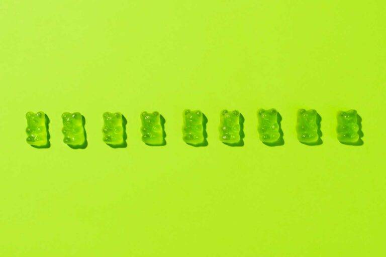 Auf dem Bild sieht man eine Reihe von grünen Gummibärchen vor einem grünen Hintergrund. Das Bild symbolisiert die Gestaltung.