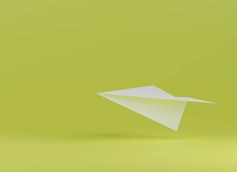 Ein Bild von einem weißen Papierflieger vor einem grünen Hintergrund. Es symbolisiert Kommunikation.
