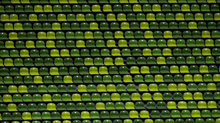 Das Bild zeigt Stadionsitze in verschiedenen Grüntönen, die das harmonische Zusammenspiel einzelner Elemente symbolisieren, die gemeinsam ein größeres Ganzes bilden.