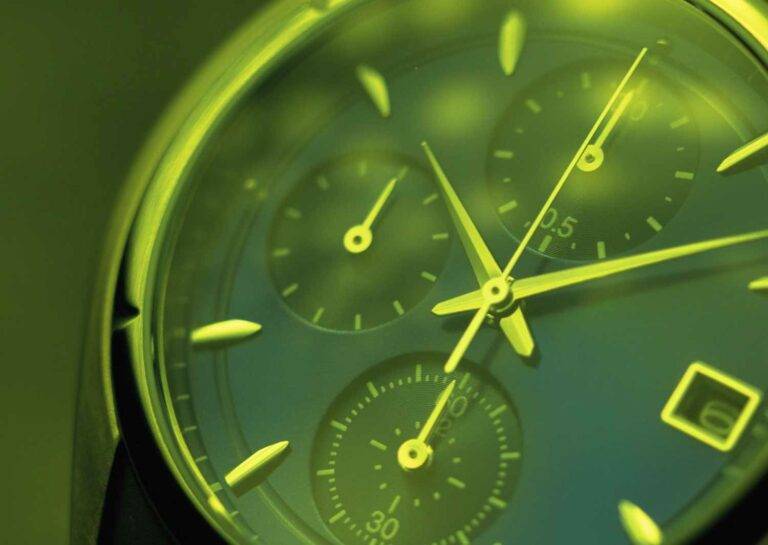 Auf dem Bild ist eine Nahaufnahme einer grünen Uhr zu sehen. Das Bild symbolisiert Zeitmanagement.