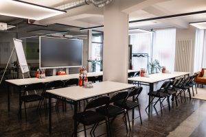 Workshopraum im GreenlightHUB München mit Reihenbestuhlung (2 Reihen), großem Screen, Flipchart und moderner Beleuchtung.