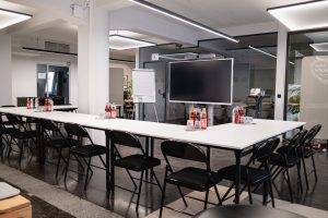 Workshopraum im GreenlightHUB München mit U-Form (U-Bestuhlung), großem Screen, Flipchart und moderner Beleuchtung.