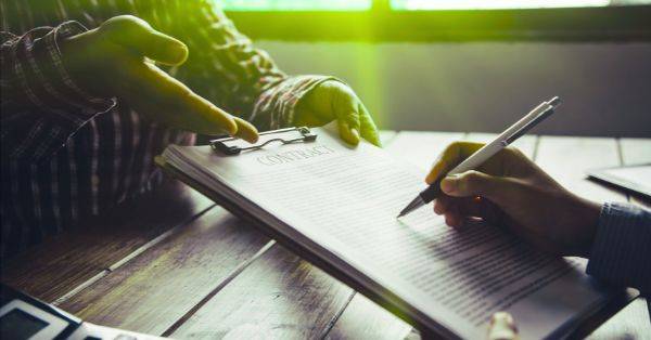 Person unterschreibt ein Dokument auf einem Klemmbrett – Symbol für effizientes Vertragsmanagement und strukturierte Vertragsprozesse im Unternehmen.