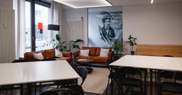 Moderner Workshop Raum mit Tischen, Stühlen und Lounge-Bereich mit Sofa in heller Büroatmosphäre – ideal für Workshops, Meetings und Teamarbeit.