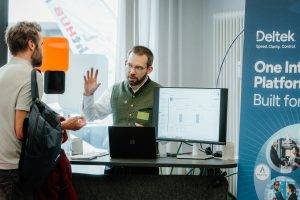 Zwei Teilnehmer im Gespräch am Deltek-Partnerstand mit Laptop und Monitor während des 20-jährigen Greenlight-Jubiläums.