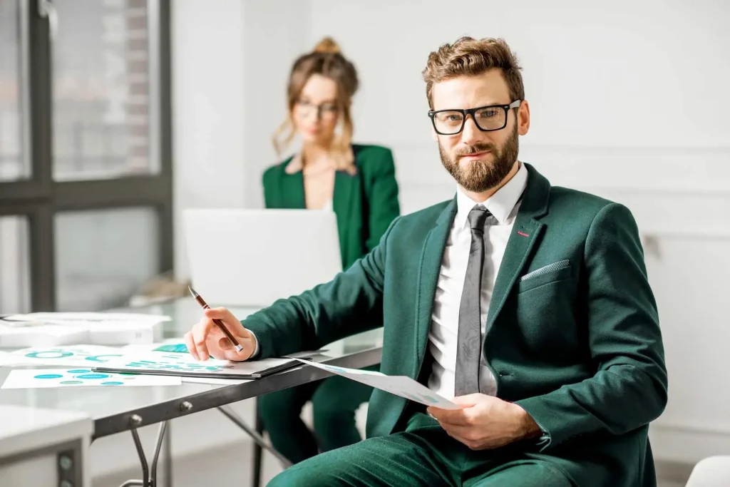Zwei freundliche Mitarbeiter von Greenlight Consulting sitzen in einem hellen und offenen Büro. Sie überzeugen mit Professionalität, Erfahrung und Sorgfalt und führen Ihr Projekt damit zum Erfolg.